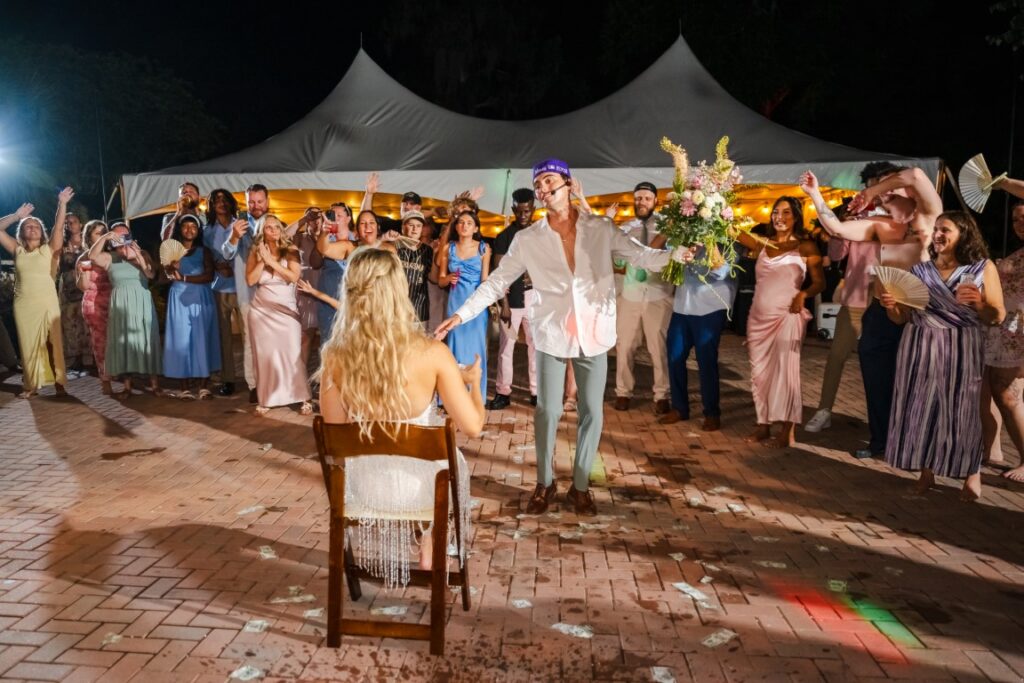 Aaron performs a Justin Bieber wedding surprise for Emily while guests gather around them at Lakeview Gardens.