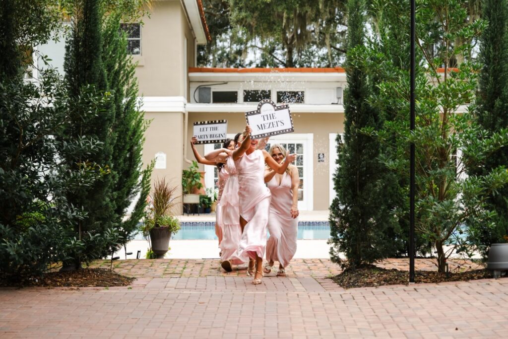 Bridesmaids celebrate with bubbles and wedding signs before Emily and Aaron's Lakeview Gardens reception.