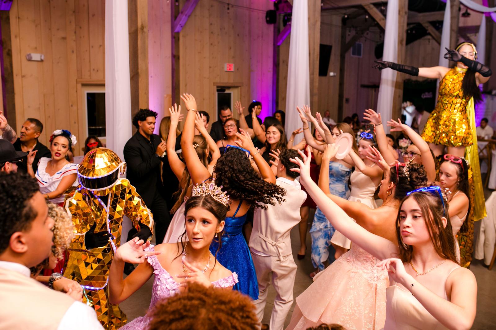 Quinceañera dancing beside a gold-costumed Hora Loca performer during the reception.