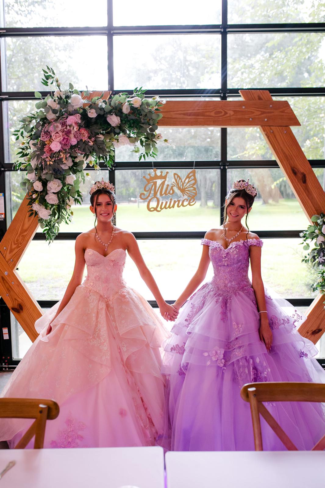 Alaina and London holding hands in their quinceañera gowns at The Barn at Hidden Oaks Farm.