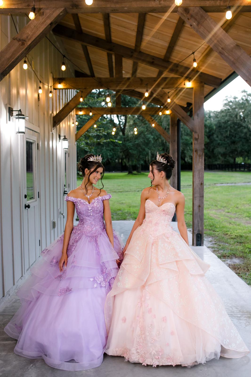 Alaina and London walking outside The Barn at Hidden Oaks Farm in Lake Mary in their quinceañera dresses.
