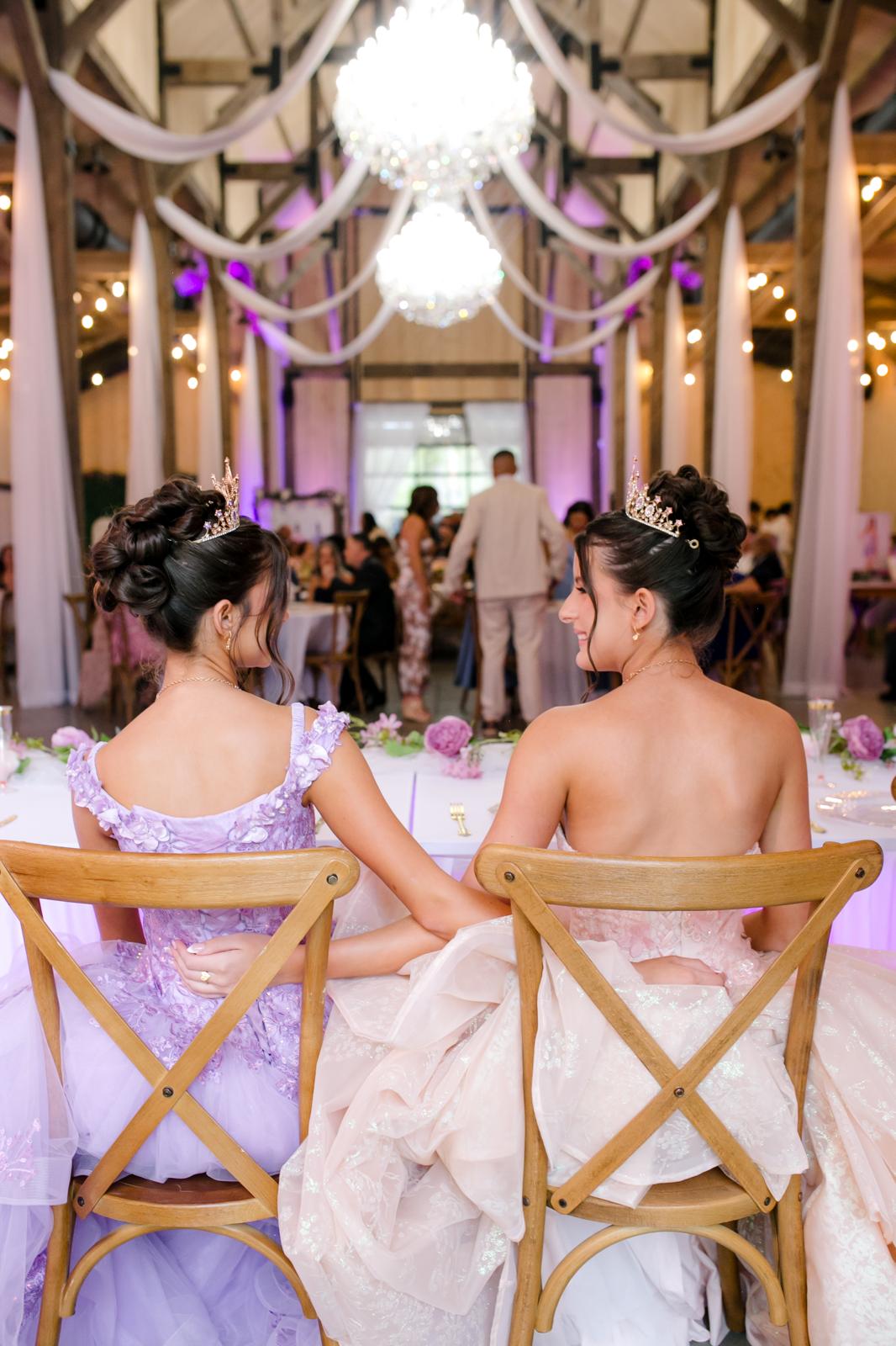 Alaina and London seated together watching their quinceañera reception inside The Barn at Hidden Oaks Farm.