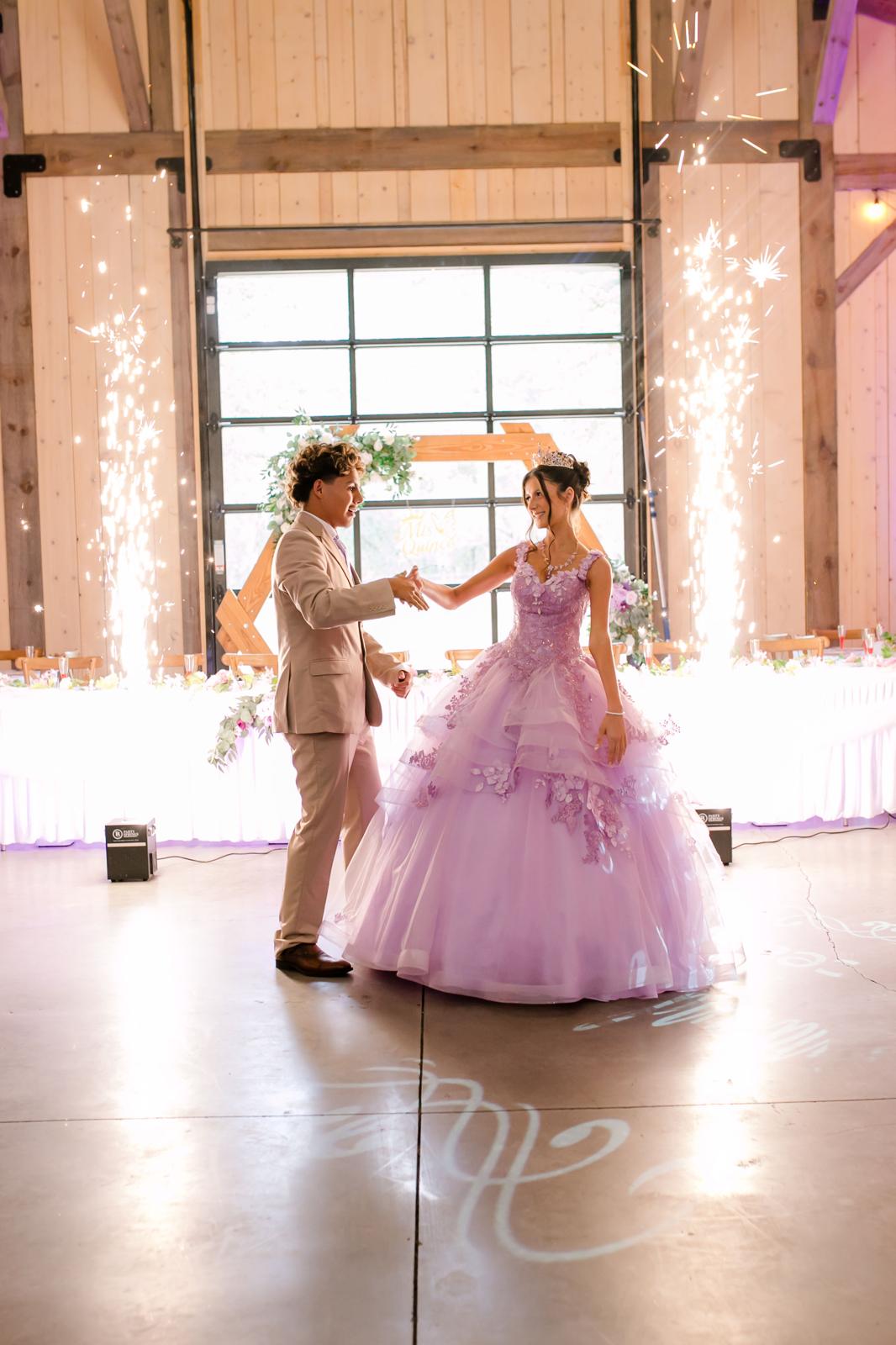 Quinceañera performing a dip during a formal dance inside The Barn at Hidden Oaks Farm