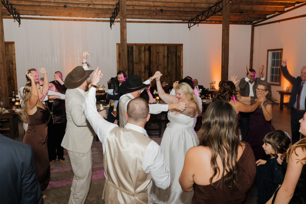 Wedding guests celebrating on a crowded dance floor during Travis and Sydney’s reception.