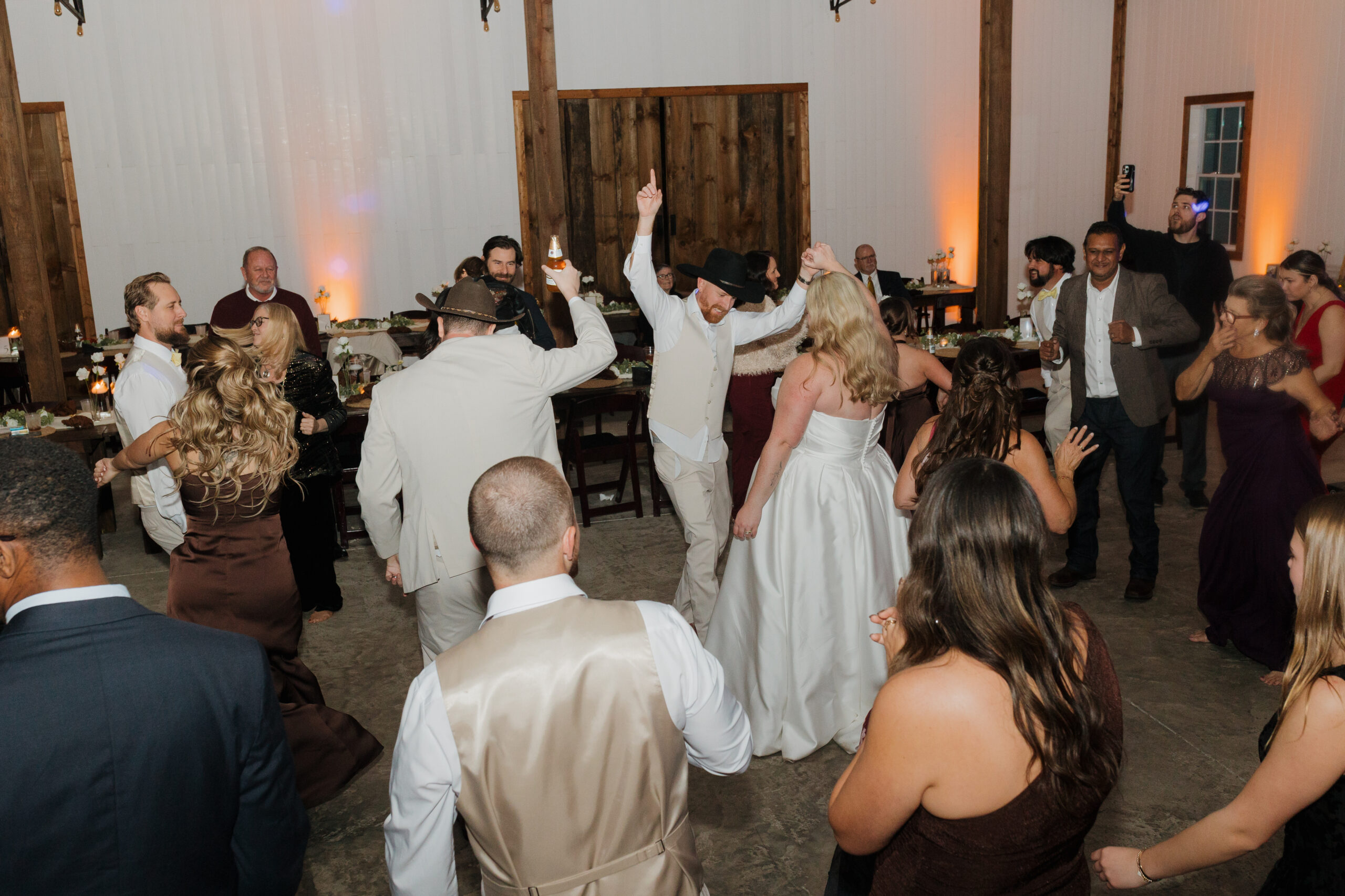 Travis and Sydney celebrating with friends and family on their packed wedding reception dance floor.